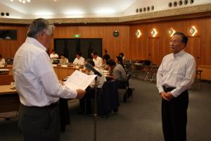 門野県教育長（左）から依頼文を受け取る田中宏二会長（岡山大学理事・副学長）