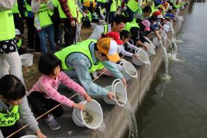 児島湖流域清掃大作戦の後に参加者と稚魚を放流する伊原木知事の写真