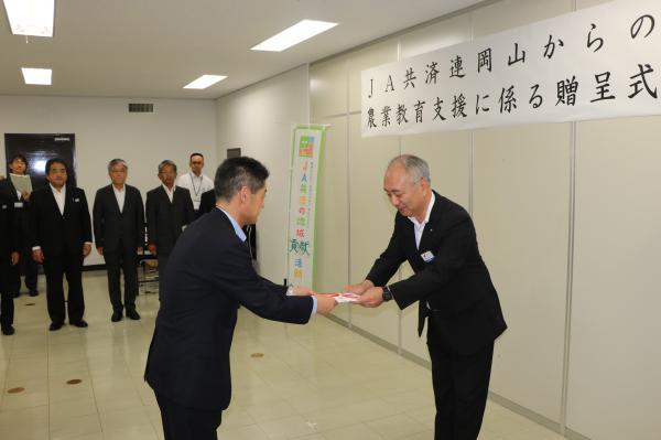▲武田一朗本部長(写真左)から目録を受け取る鍵本県教育長