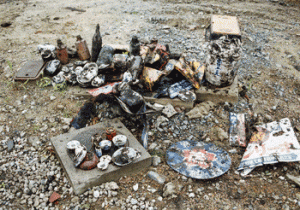掘り出されたばかりのゴミ。手前にホーロー看板、その奥に陶器製の醤油樽が見える。