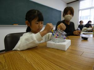 ランタンに色塗りをしている子供を親が見守っている写真