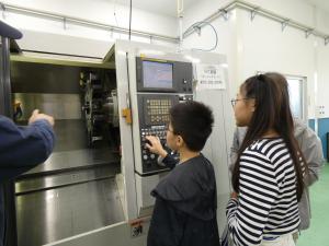 指導員と一緒にNC旋盤を操作する参加者の写真