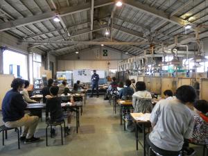 指導員の説明を聞く参加者の全体写真