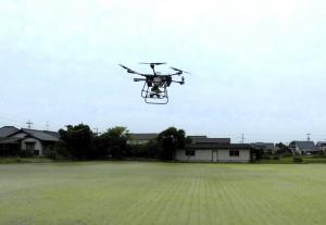 ドローンが田んぼの上を飛行し、薬剤を撒いている様子