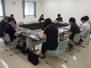 机を囲み、情報交換が行われる様子