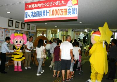 県立図書館の個人貸出冊数１０００万冊突破を祝して来館者を職員が出迎える写真