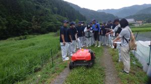 高校生がラジコン草刈機の操作を体験しています